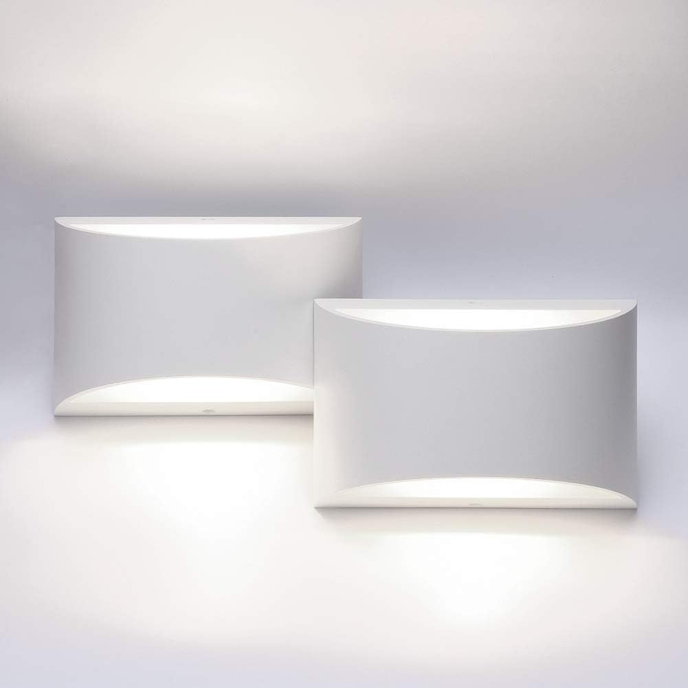Two white wall sconces side by side, each casting soft warm light upward and downward.
