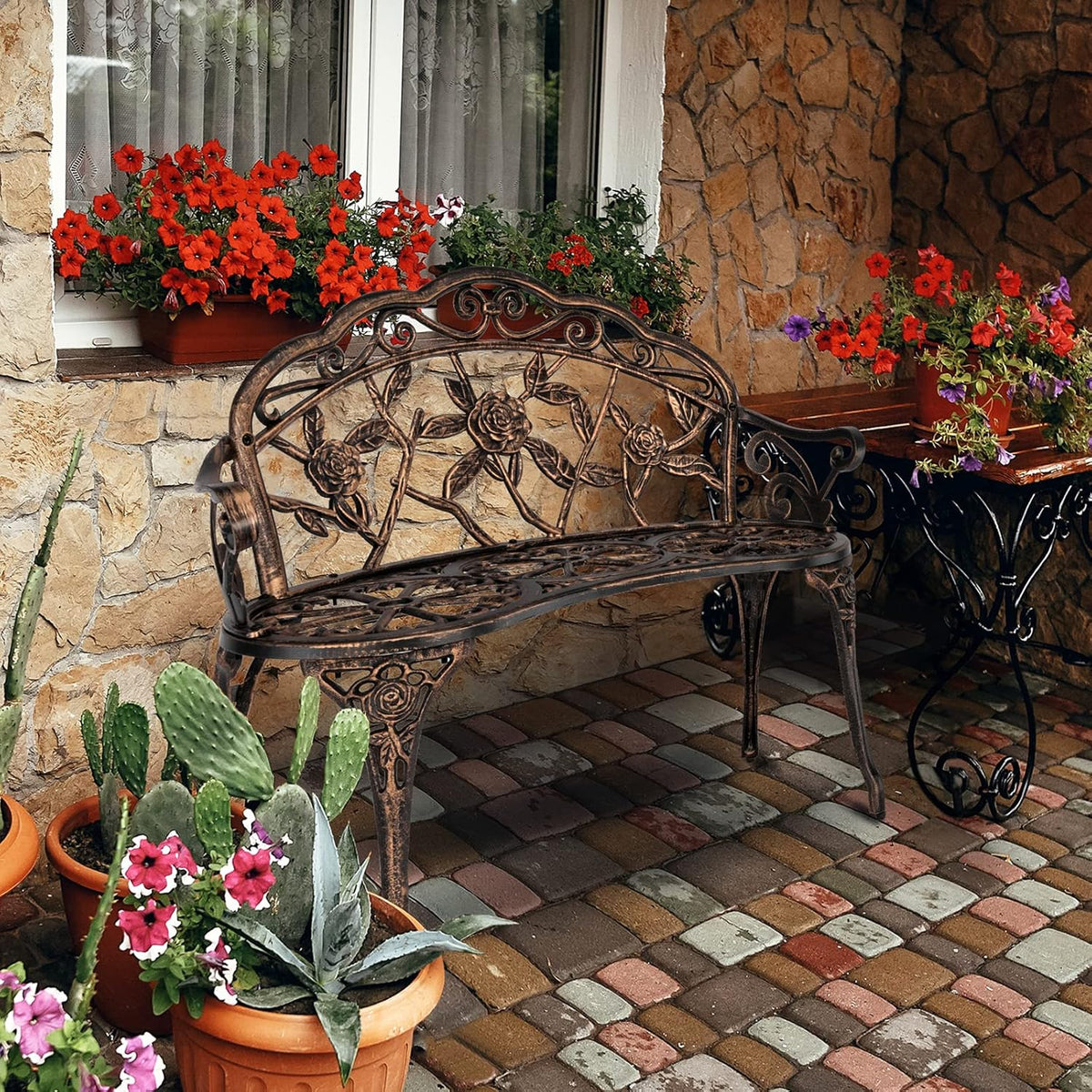 Bronze decorative garden bench on a stone patio among potted flowers