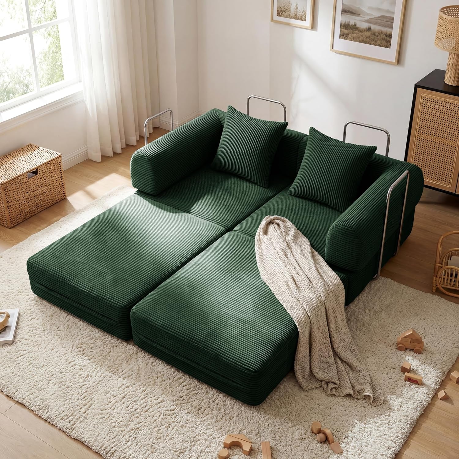 Top-down view of a dark green corduroy folding sofa bed opened flat with pillows and a throw on a shag rug.