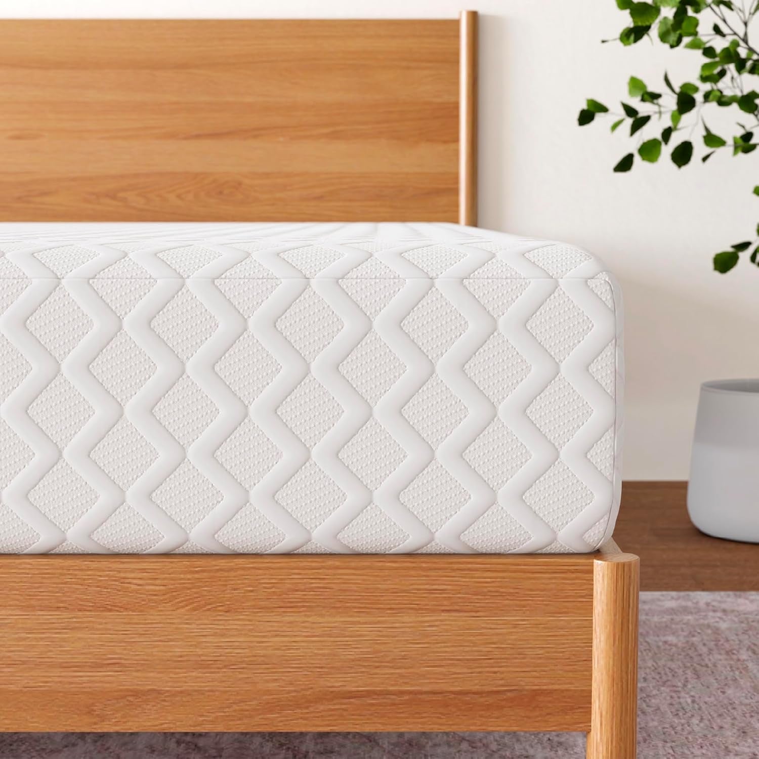 Close-up of the mattress edge showing white diamond-quilted fabric and textured stitching over a wood bed frame.