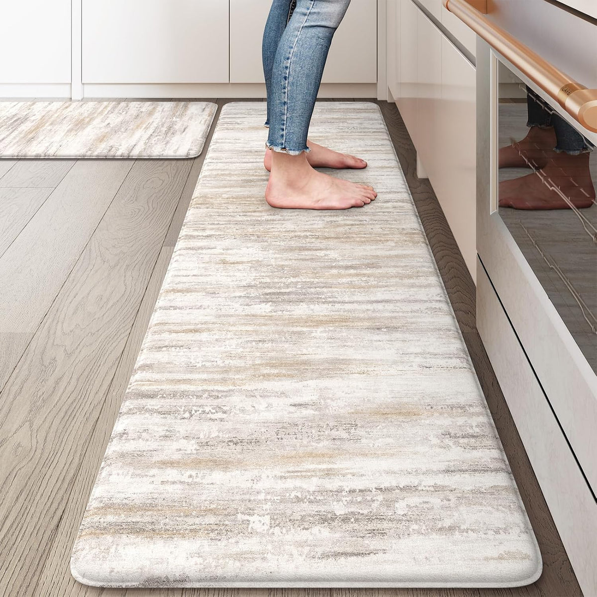 Close-up of a beige abstract anti-fatigue kitchen mat with bare feet standing on it