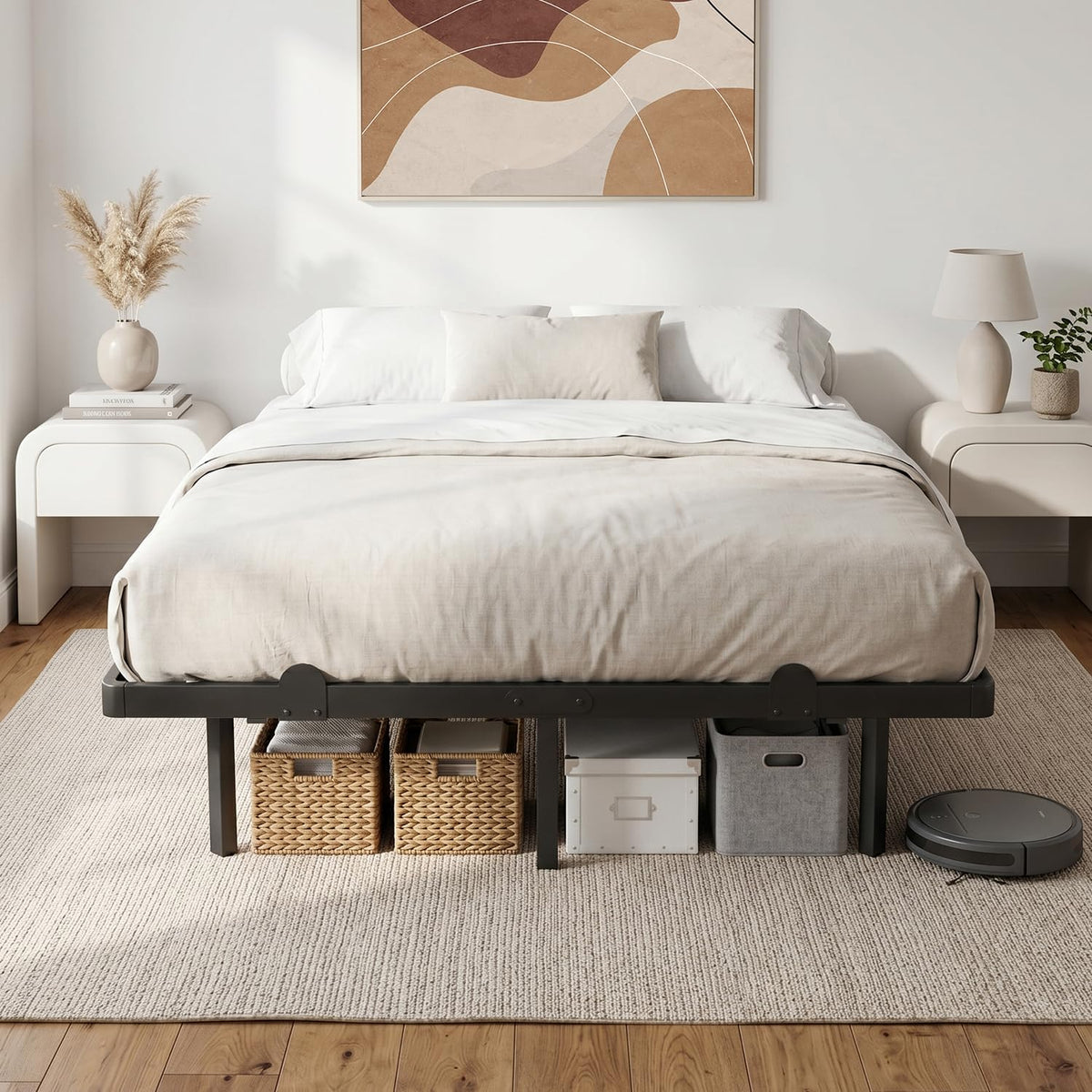 Front bedroom scene showing the black metal frame at foot of a dressed bed, wall art, bedside decor and a robot vacuum
