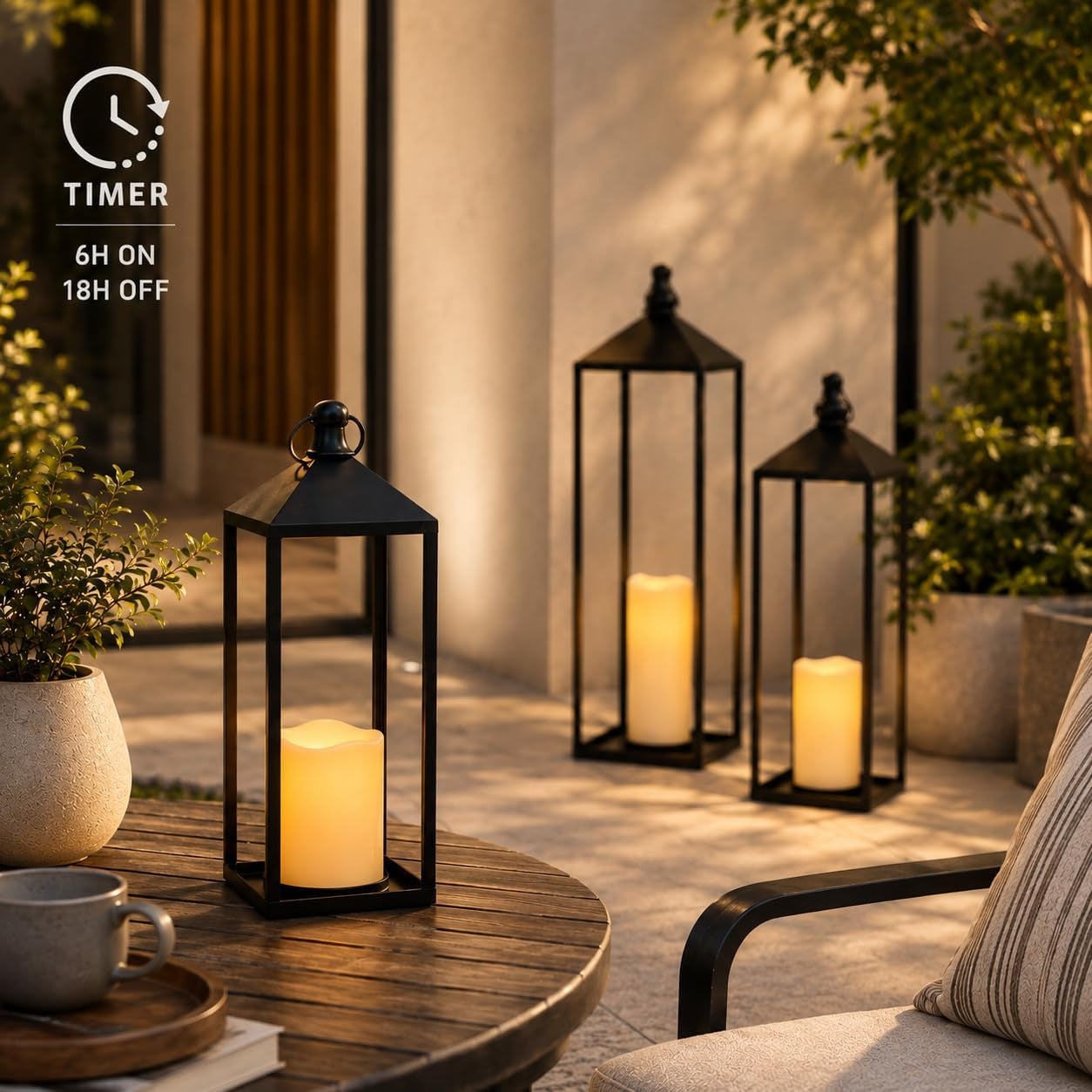 Three black lanterns with glowing LED candles on a patio at dusk demonstrating the timer function in use