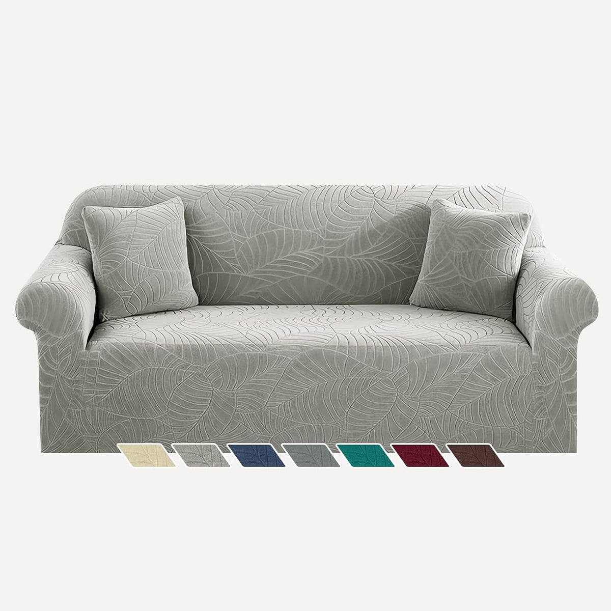 Sofa draped in a leaf-patterned gray slipcover with two matching throw pillows.