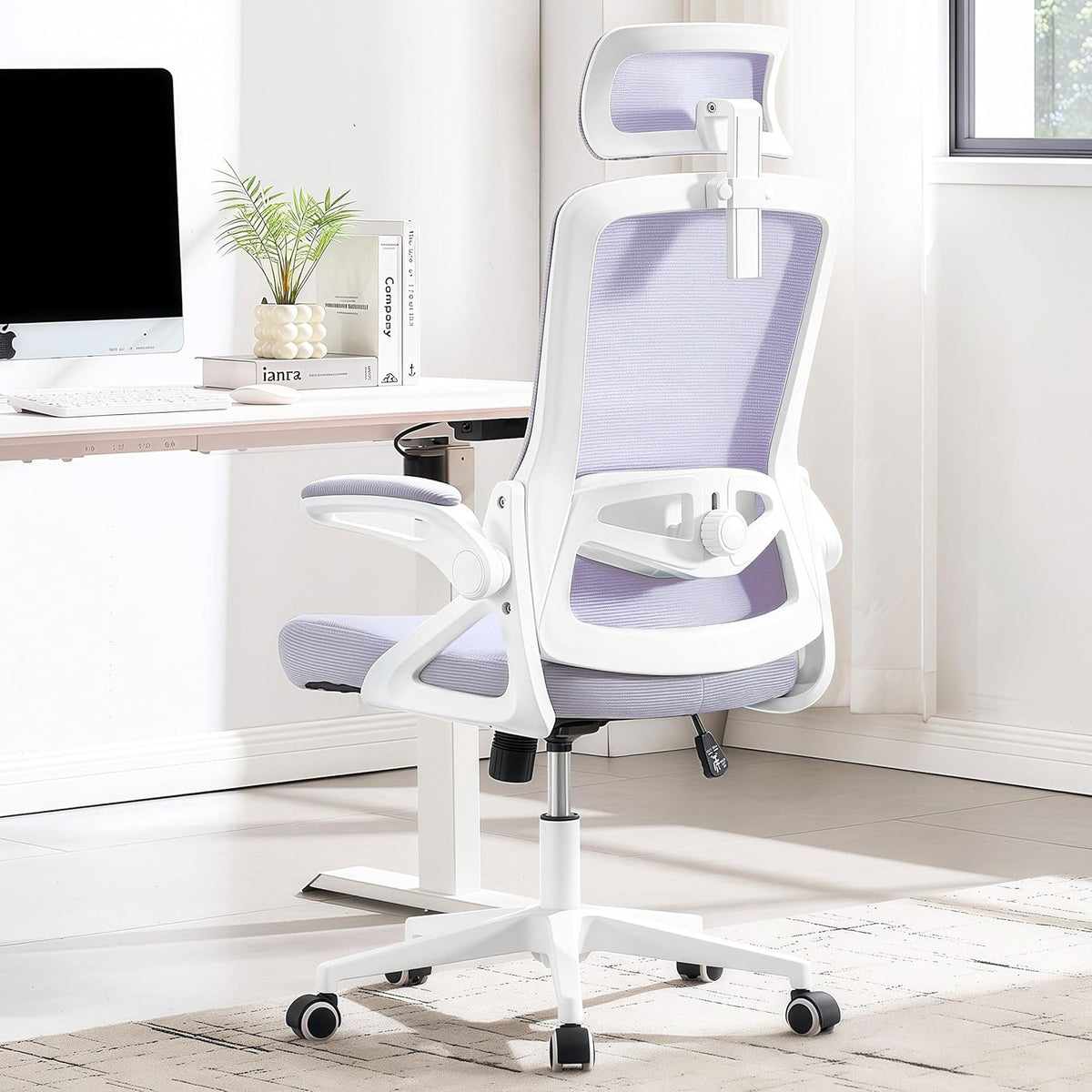 Rear three-quarter view of a white-framed office chair with light lavender mesh back and matching seat in a bright workspace.