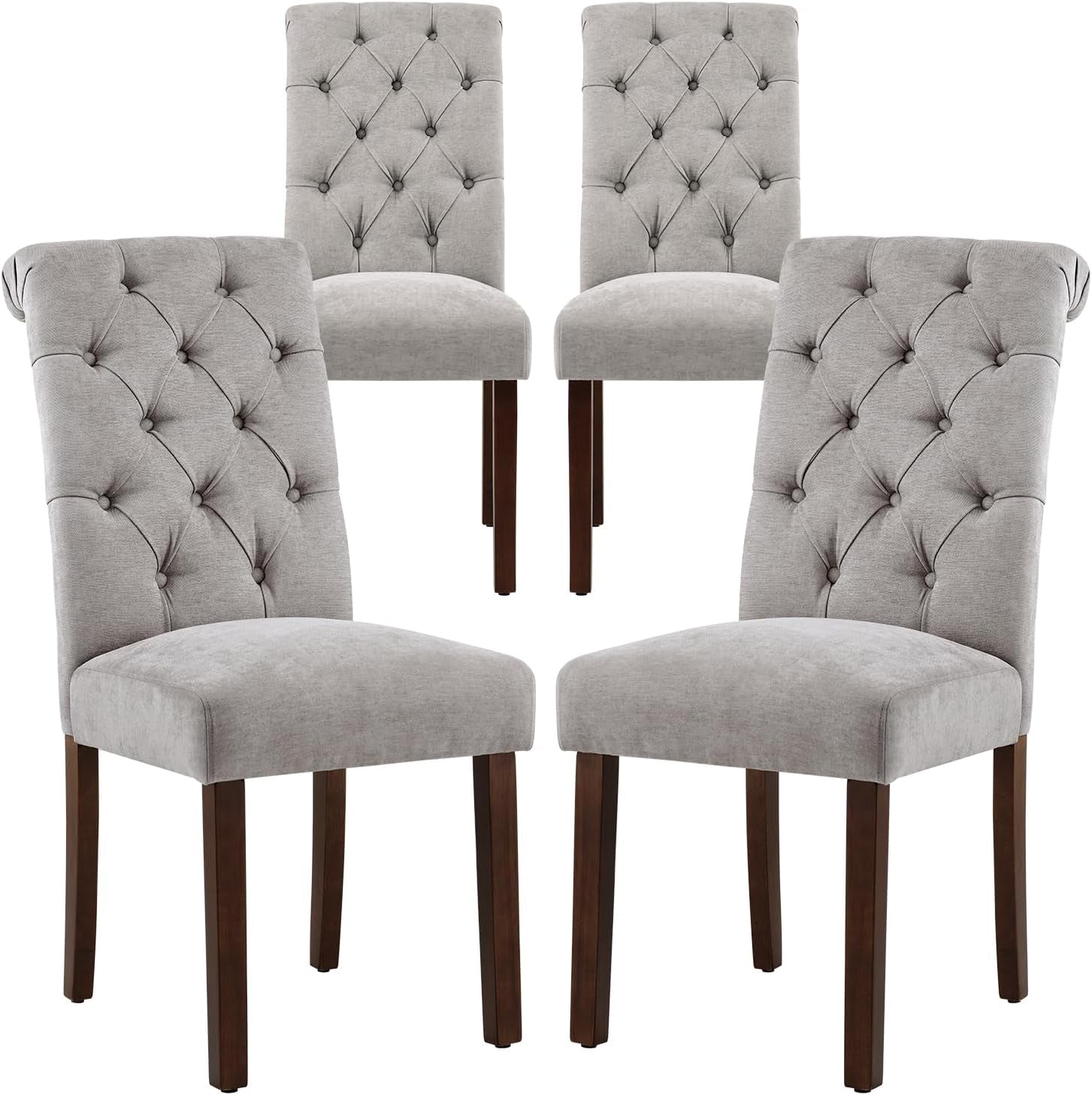 Four light gray tufted dining chairs with button detailing and brown wood legs
