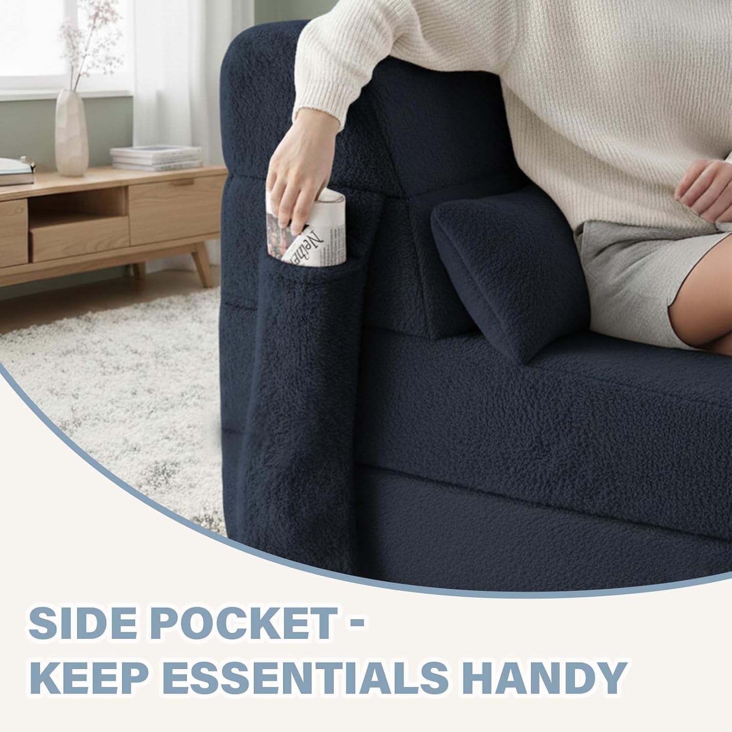 Close-up of a navy folding sofa arm with a built-in side pocket holding a rolled magazine