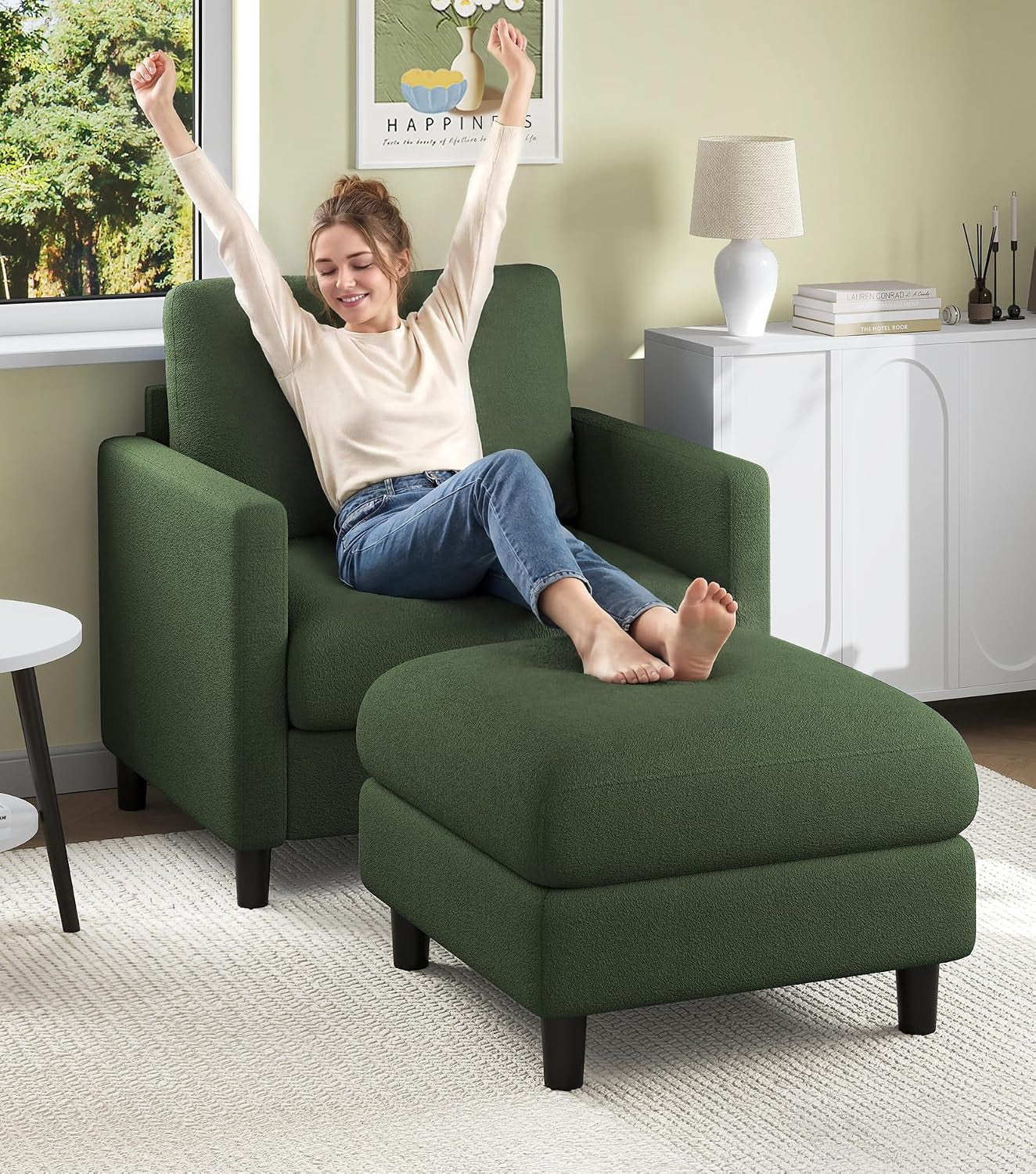 Woman stretching back with arms raised while reclining on a green armchair with matching ottoman in a bedroom corner.