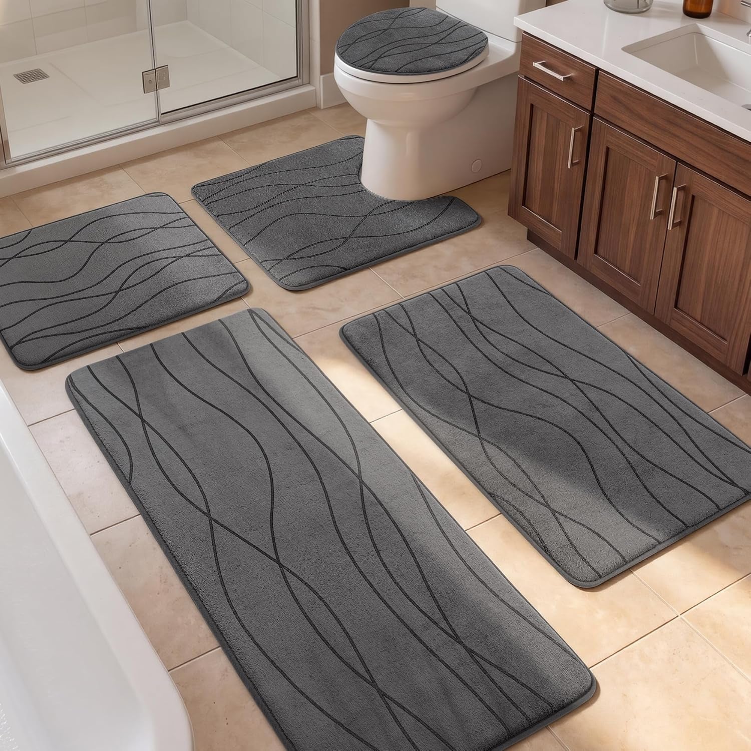 Dark grey bathroom rug set placed around toilet and tub in a tiled bathroom, front perspective view showing cabinet and floor