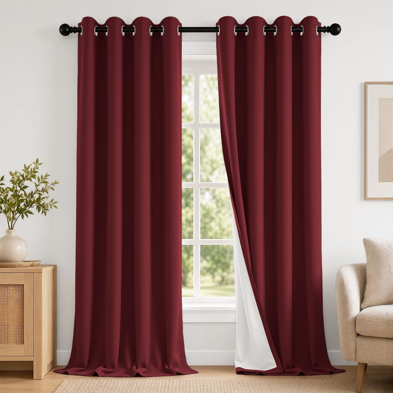 Pair of deep burgundy grommet curtains hung at a window, one panel pulled back to show white backing