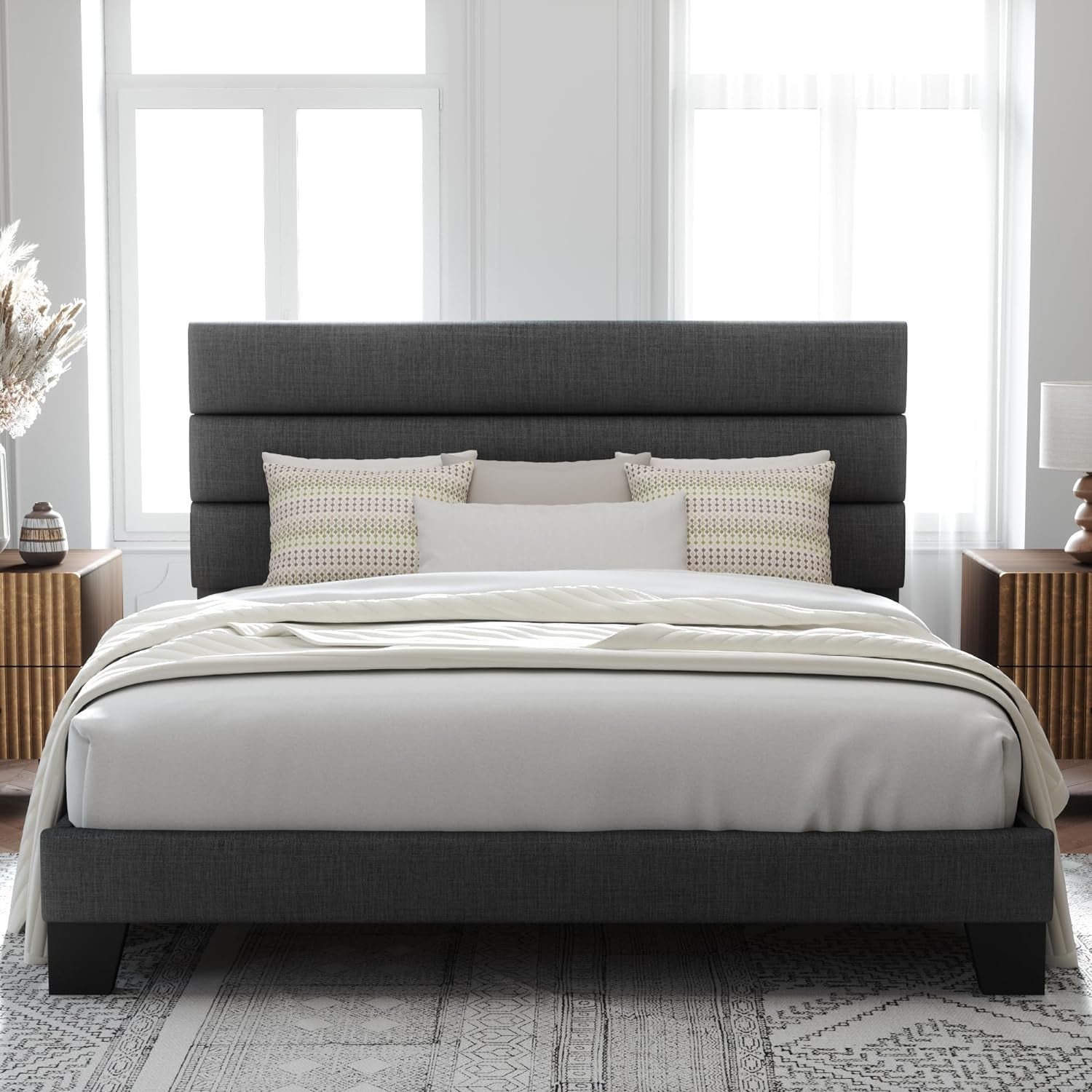 Centered room shot of a dark gray bed with white bedding, three-panel headboard and two nightstands.