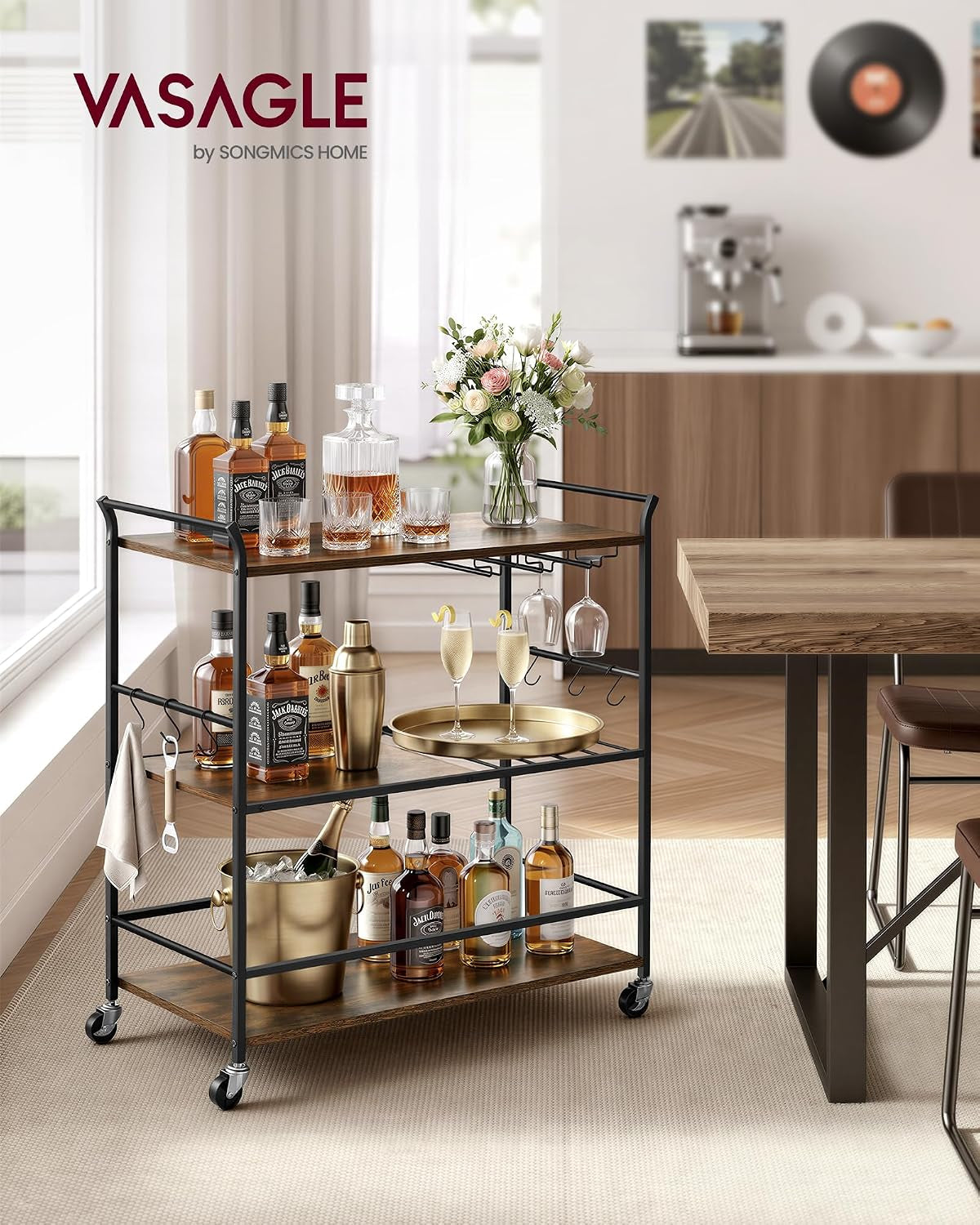 3-tier serving cart staged as a home bar with decanter, bottles, glassware, and hanging S-hooks beside a dining table