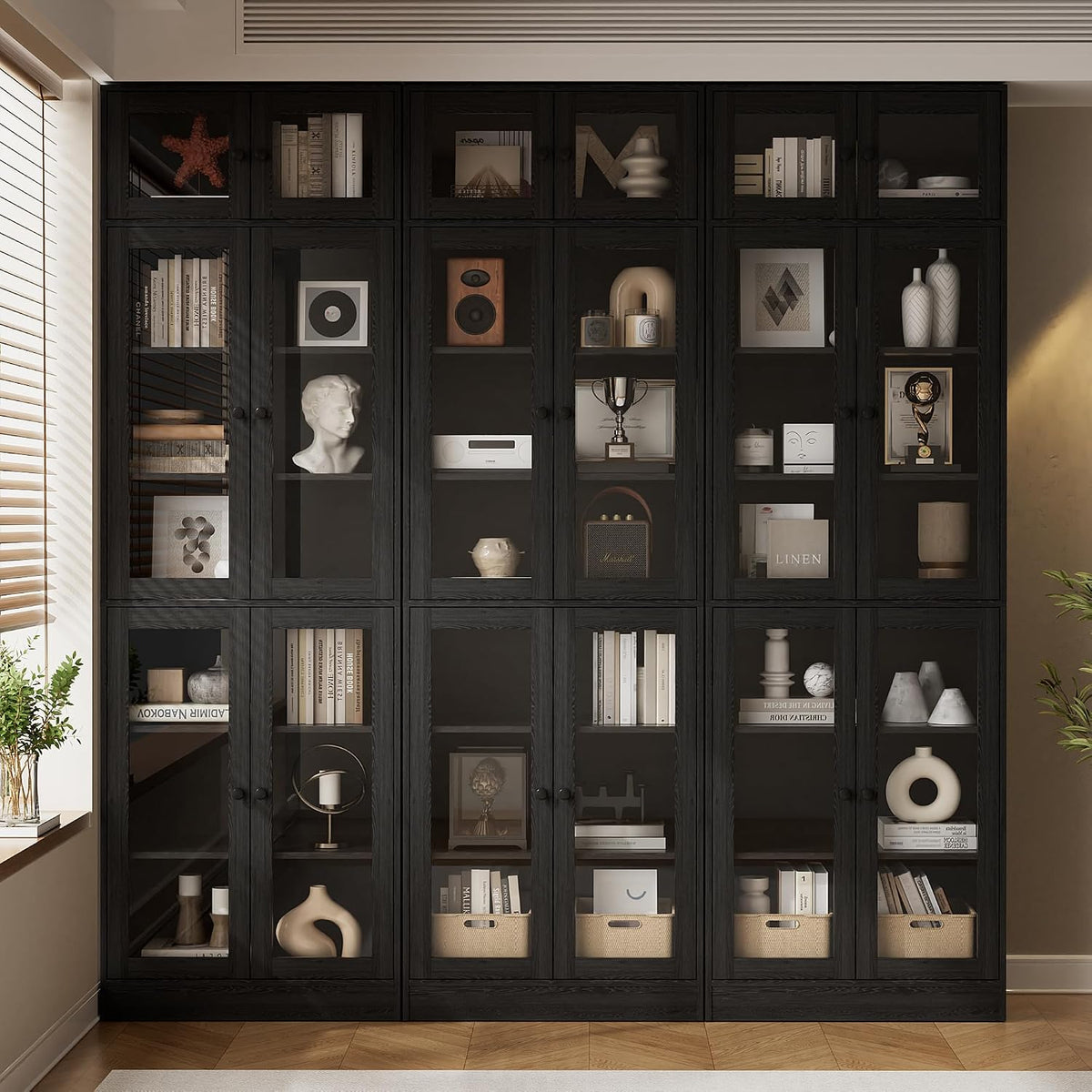 Black 7-tier bookcase with glass doors filled with books, baskets and decorative objects in a room setting.