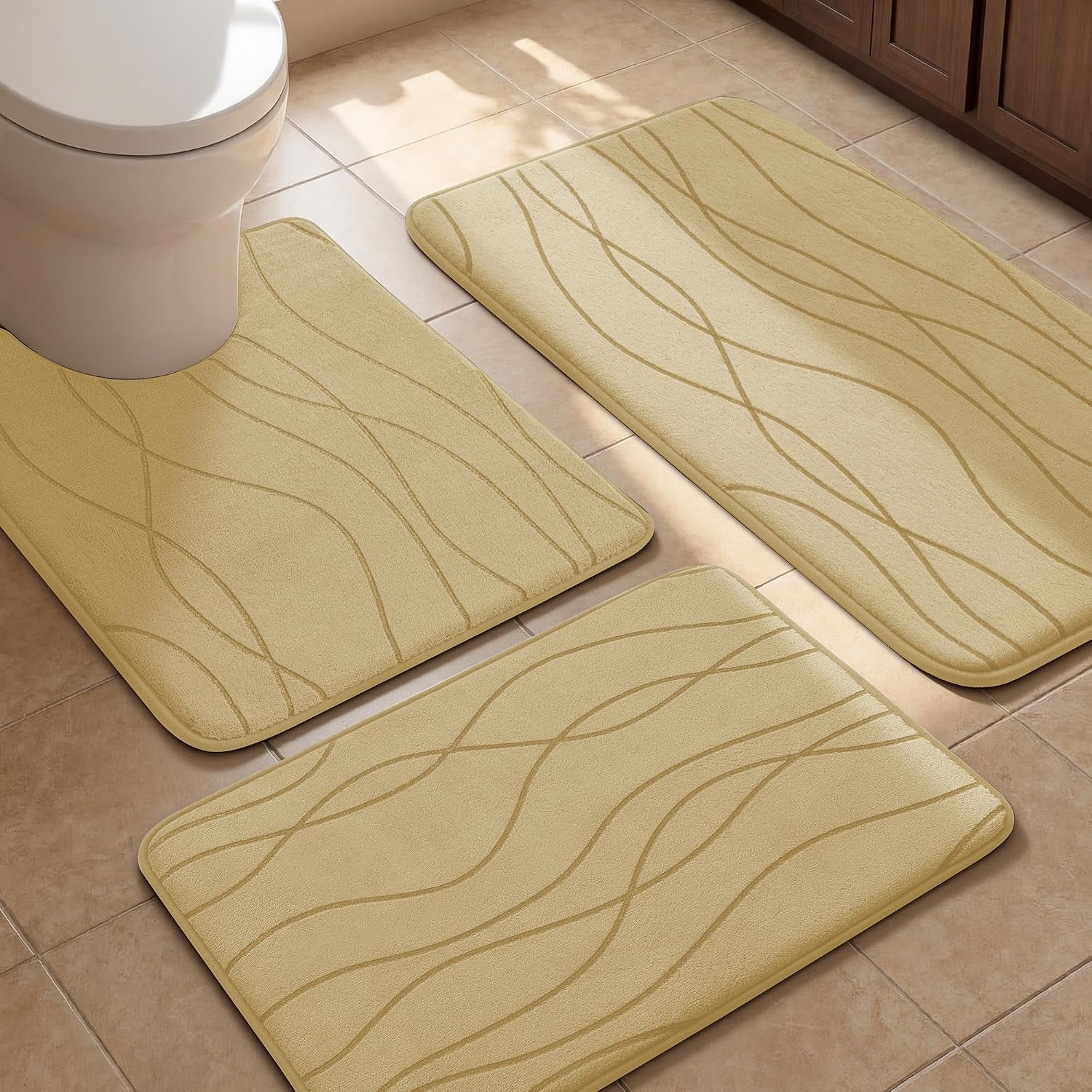 Three pale beige mats with subtle wavy lines positioned around a toilet on tiled floor