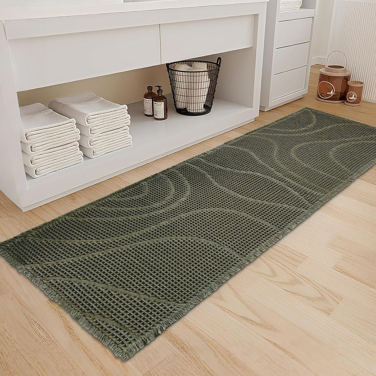 Olive green runner with a wavy non-slip pattern laid in front of a white open-shelf vanity.