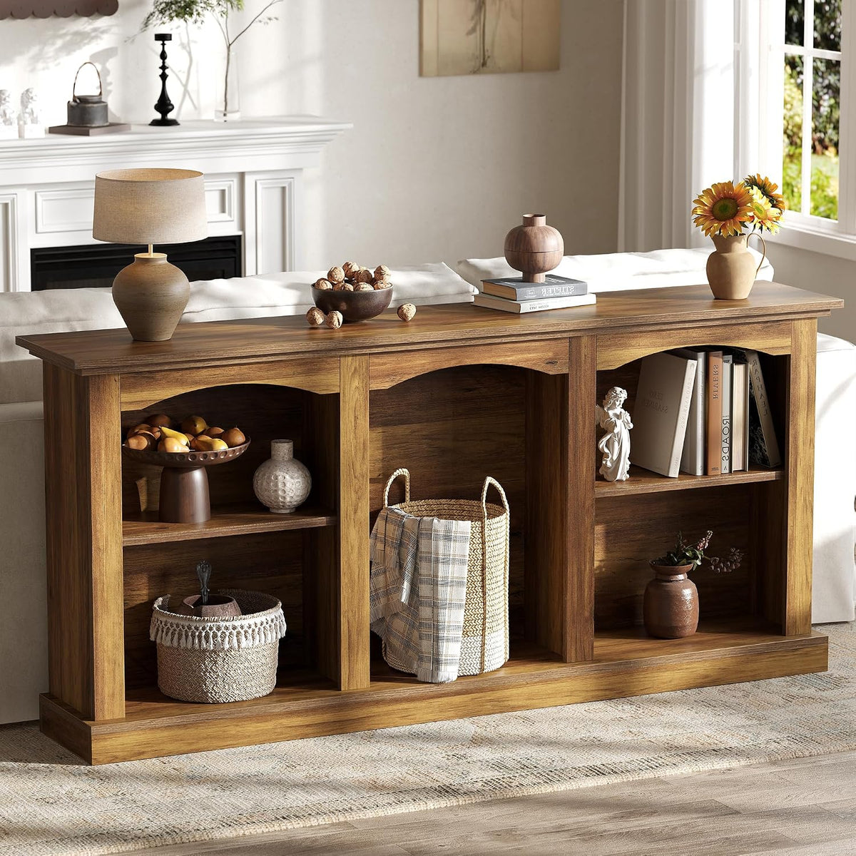 Console table shown behind a sofa with decorative bowls, lamp, and stacked books on the tabletop