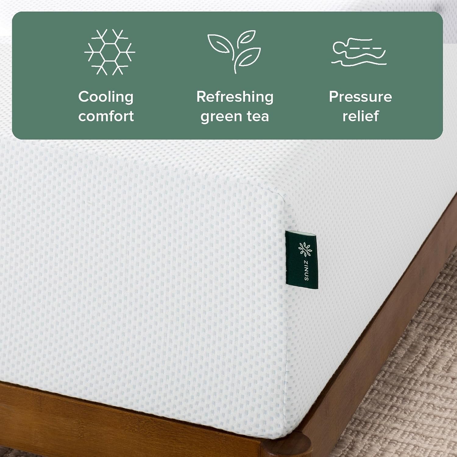 Close-up corner of white knitted mattress cover with a small fabric tag and icons for cooling and green tea.