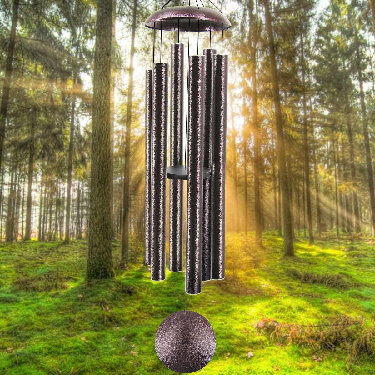 Close-up of six-tube metal wind chime hanging in a sunlit forest background.