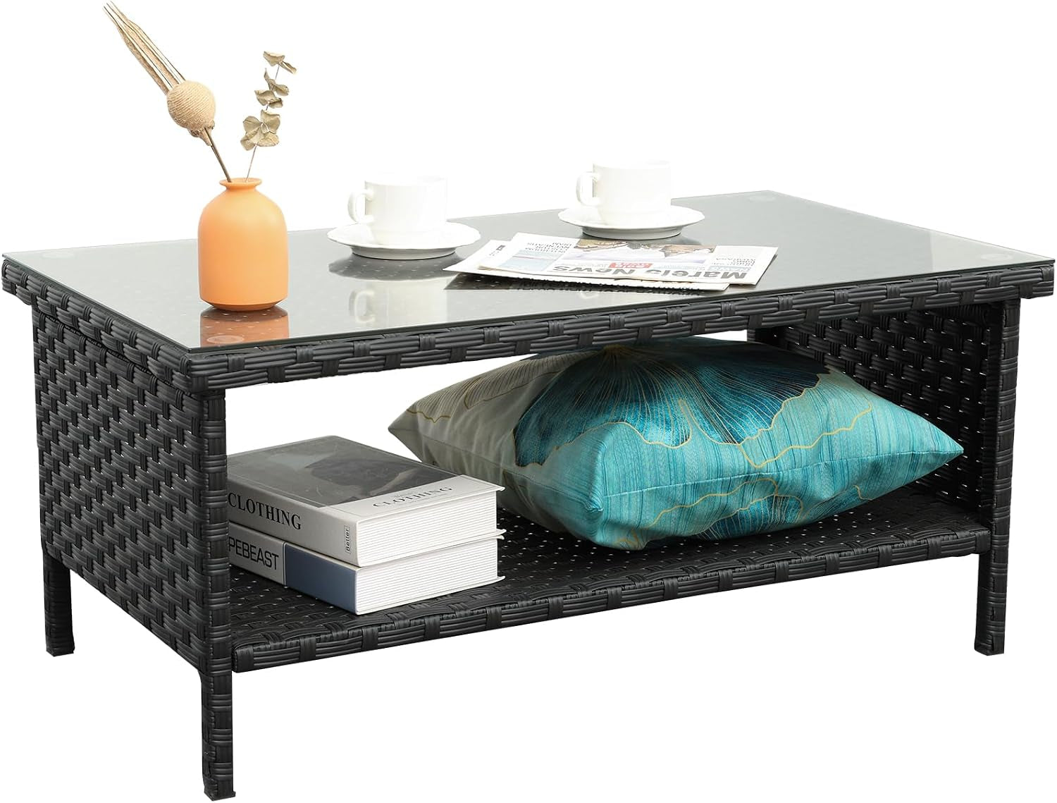 Side view of charcoal wicker outdoor storage table with teal pillow and stacked books on lower shelf.