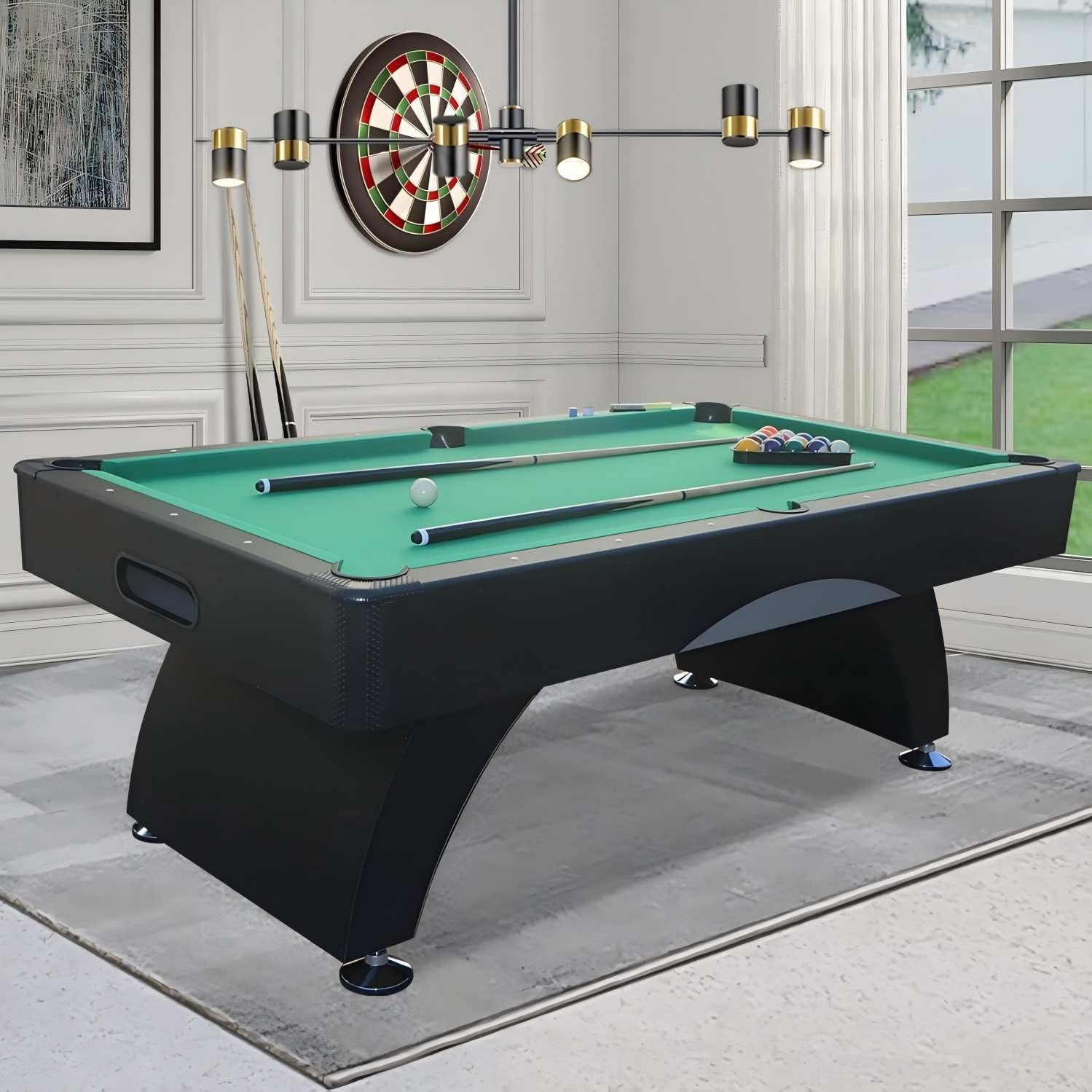 Three-quarter view of a black pool table with green felt, two cues, cue ball and racked balls in a bright room.