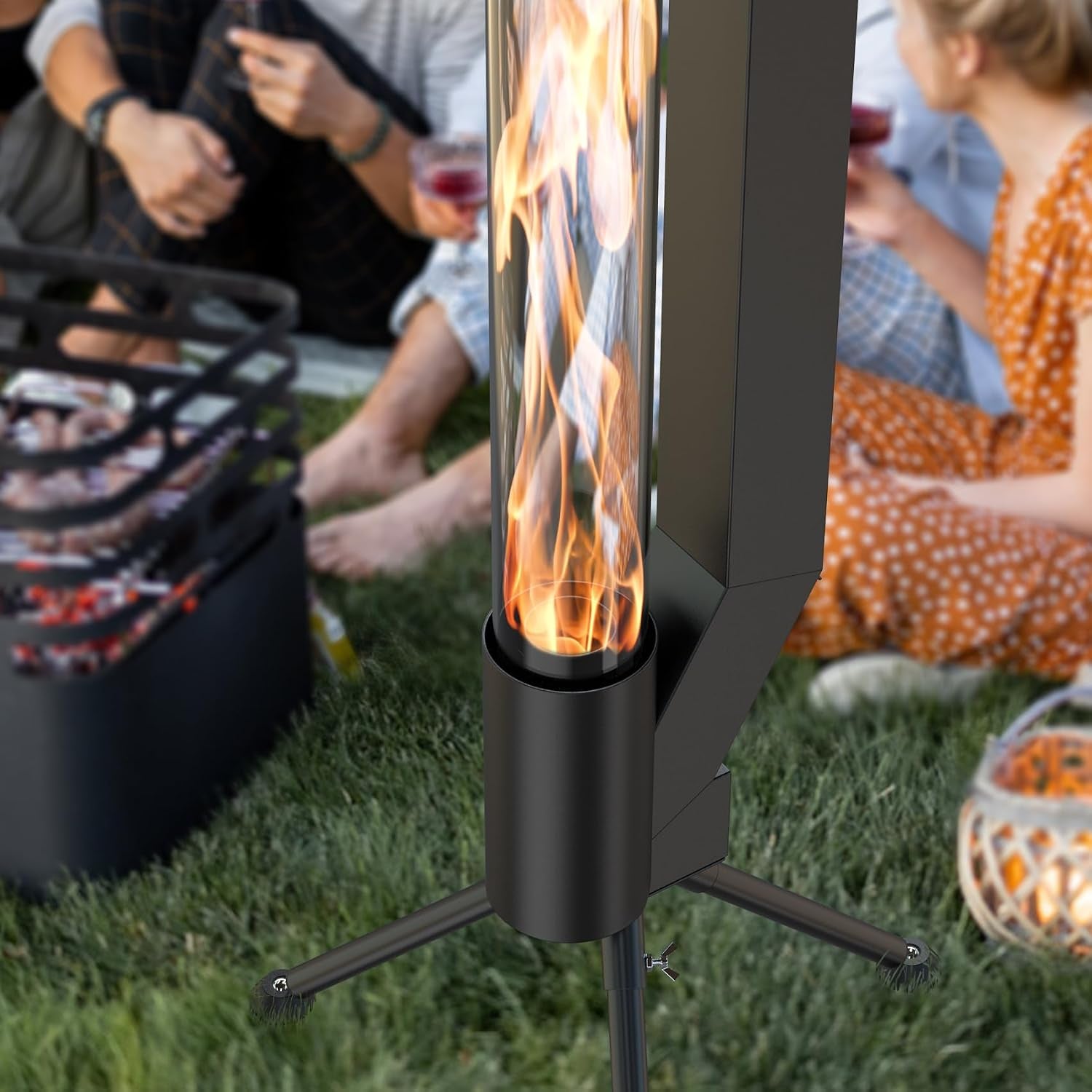 Close-up of the glass flame tube and lower burner mounted on tripod legs on grass with people in background.