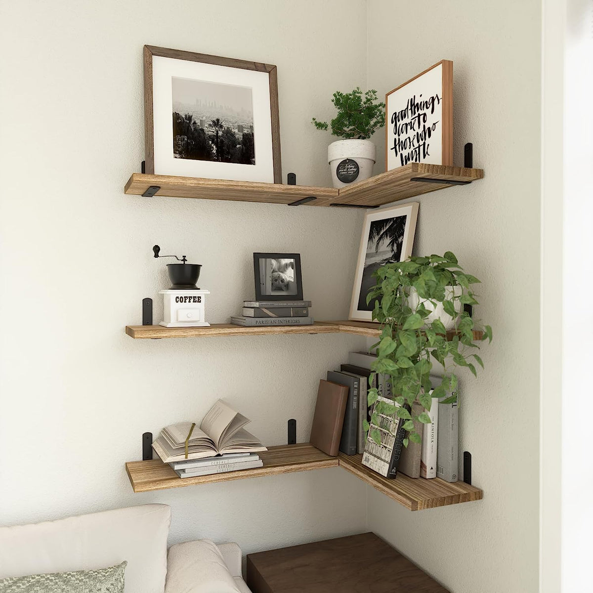 Corner installation of three rustic wood floating shelves forming an L with plants, books, and framed art