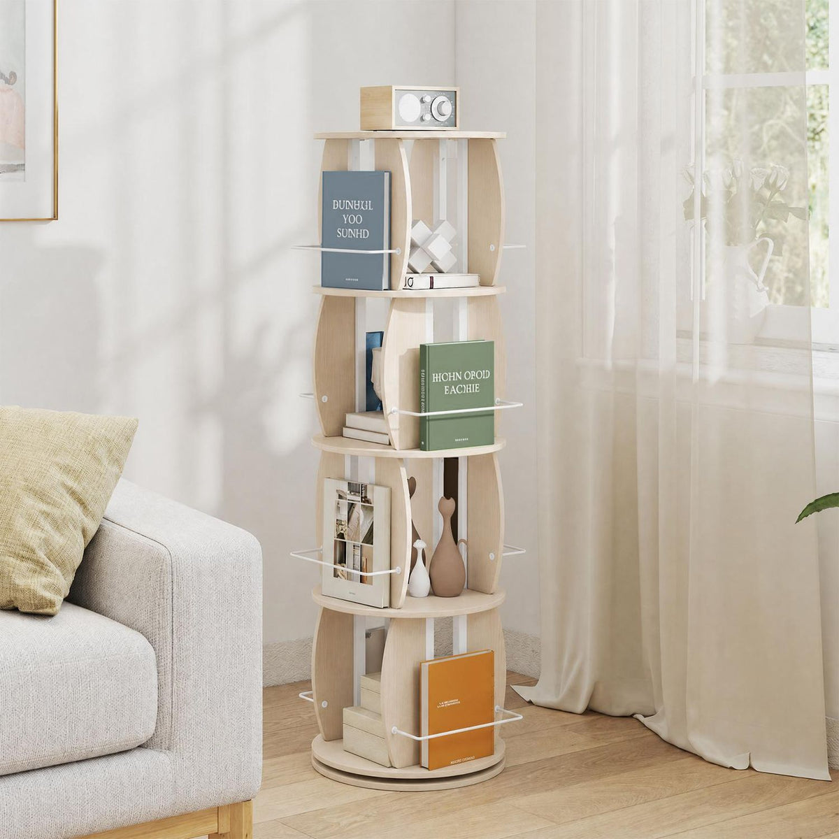 Light wood rotating bookcase filled with books and decor beside a sofa and curtained window.
