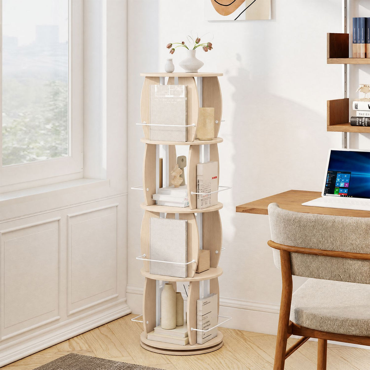 Four-tier light wood bookcase displayed beside a desk and window, holding books and decorative objects.