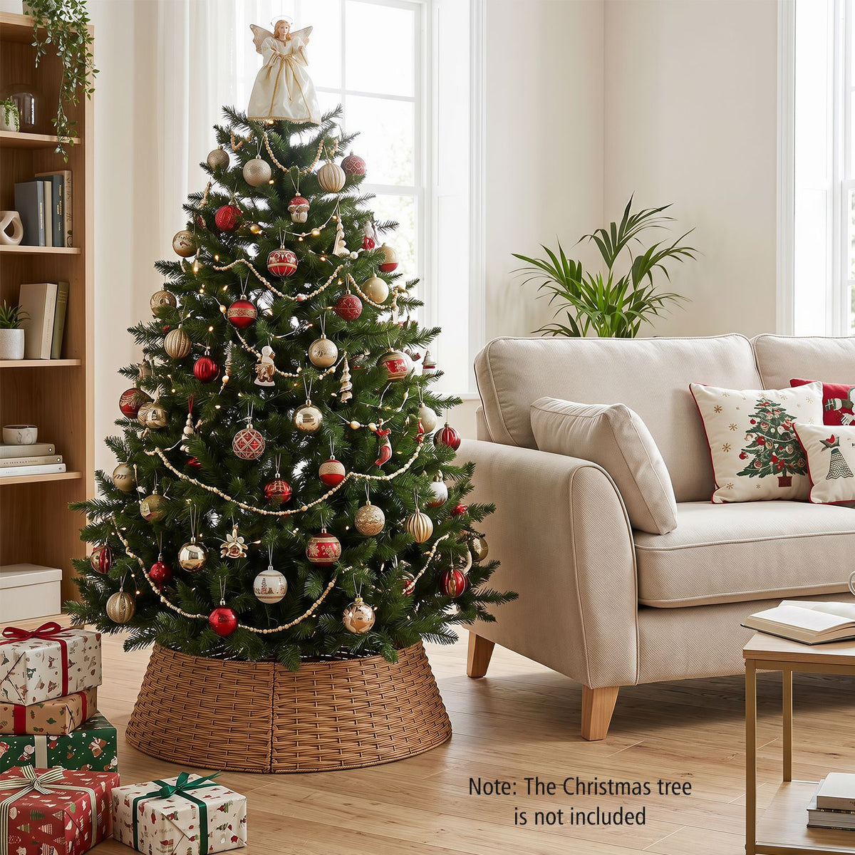 Decorated Christmas tree stands inside a woven brown collar beside a cream sofa and wrapped gifts.