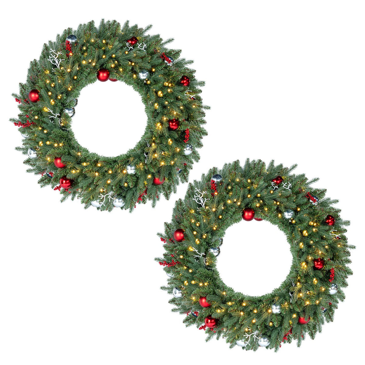 Two matching evergreen wreaths decorated with warm lights, red ornaments, berries, and white accents on a white background.