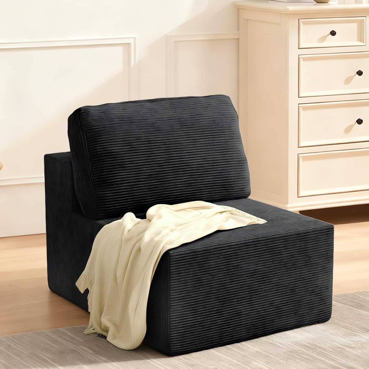 Three-quarter view of a single black modular seat with a light cream throw on the cushion.