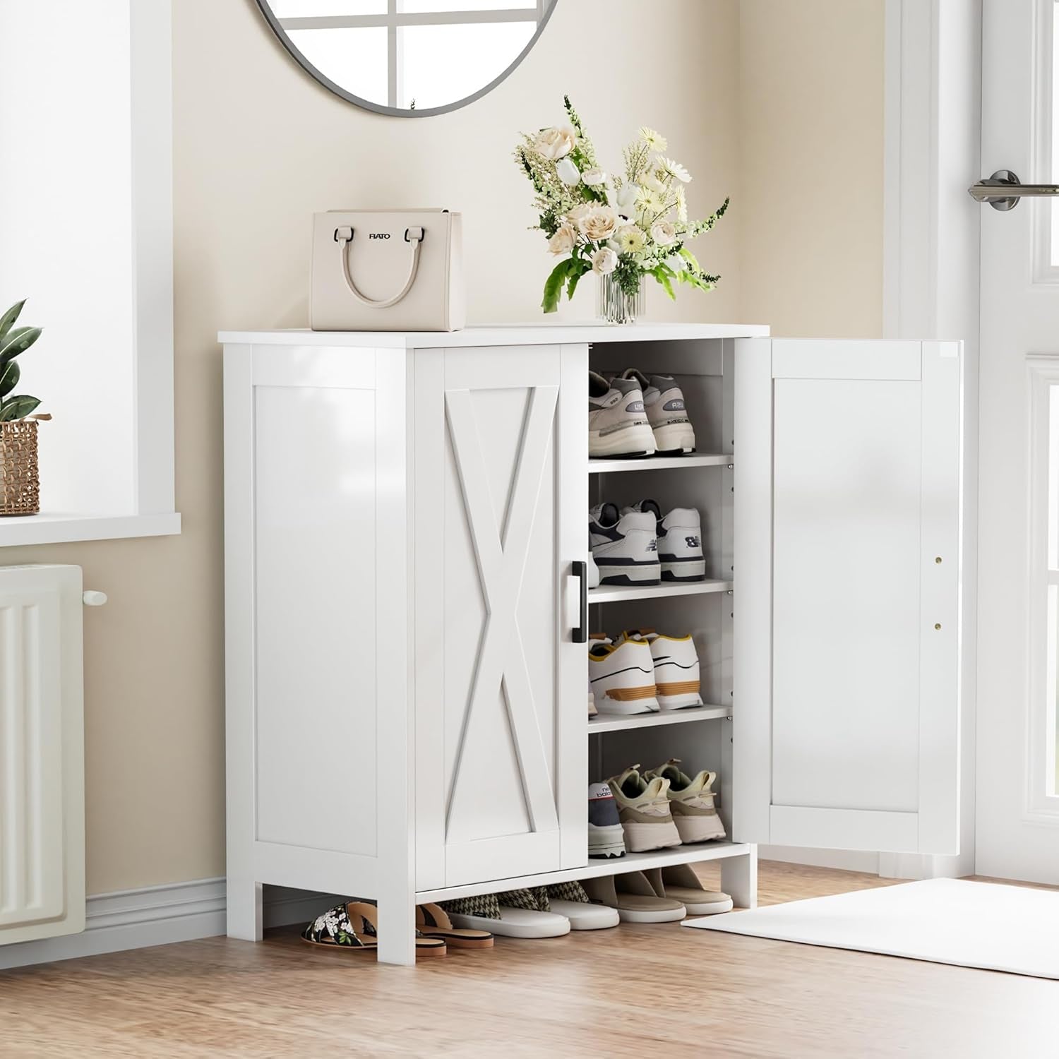 White shoe cabinet in a bright entryway, one door open to show organized shoes and a purse and flowers on top.