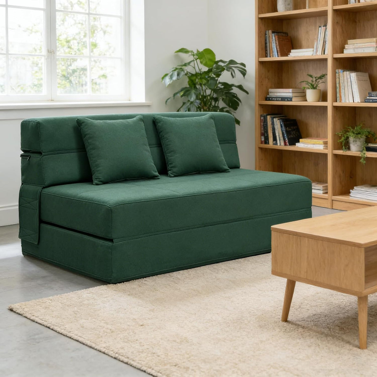 Green folding futon sofa bed set in a bright room with bookcase and wooden coffee table