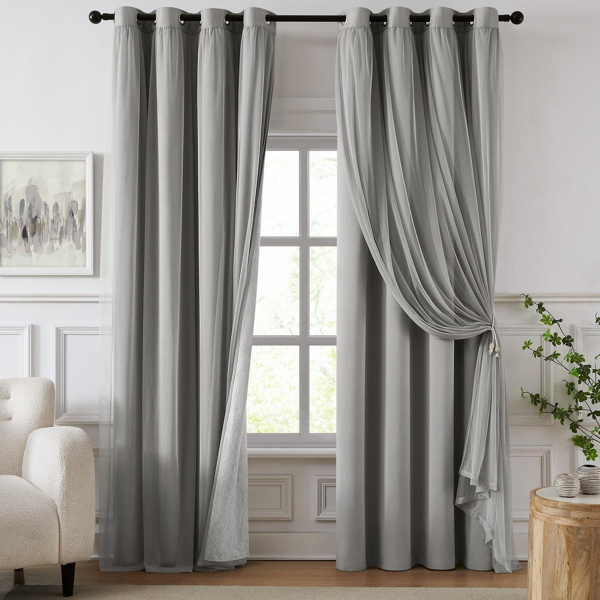 Window dressed in light gray blackout panels with a sheer overlay tied to one side.