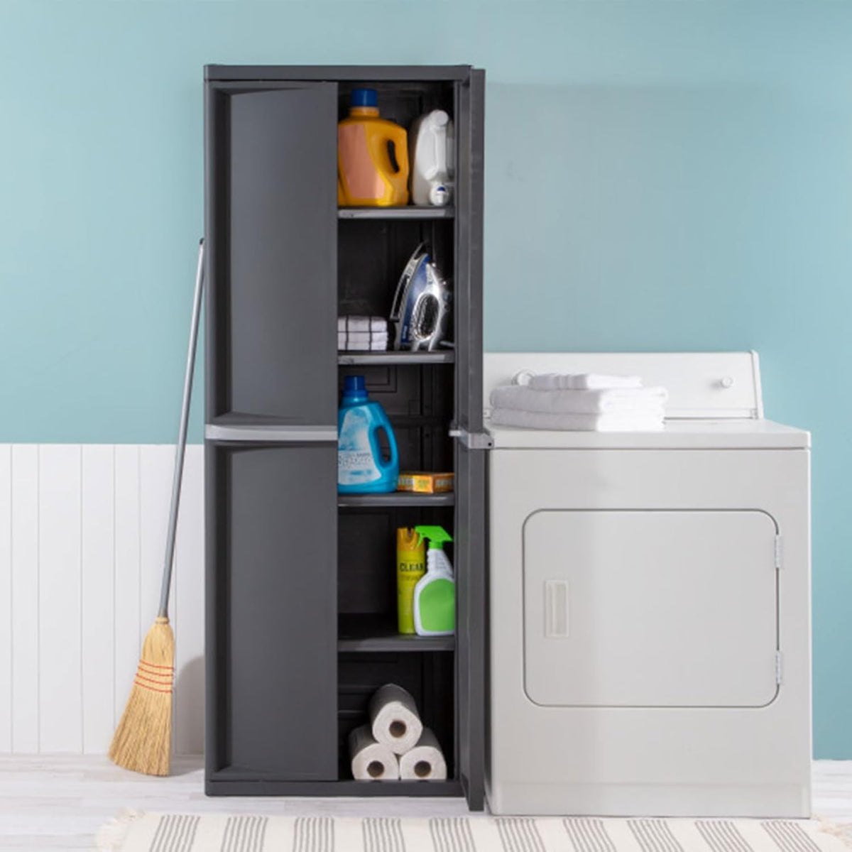Gray storage cabinet with one door open next to a dryer in a laundry room setting showing cleaning supplies on shelves.