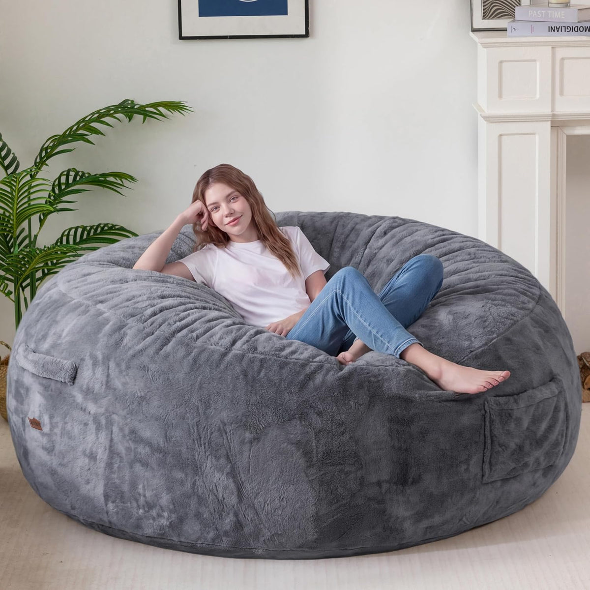 Woman reclining sideways on a gray bean bag, propped on one elbow with a visible fabric handle on the side.