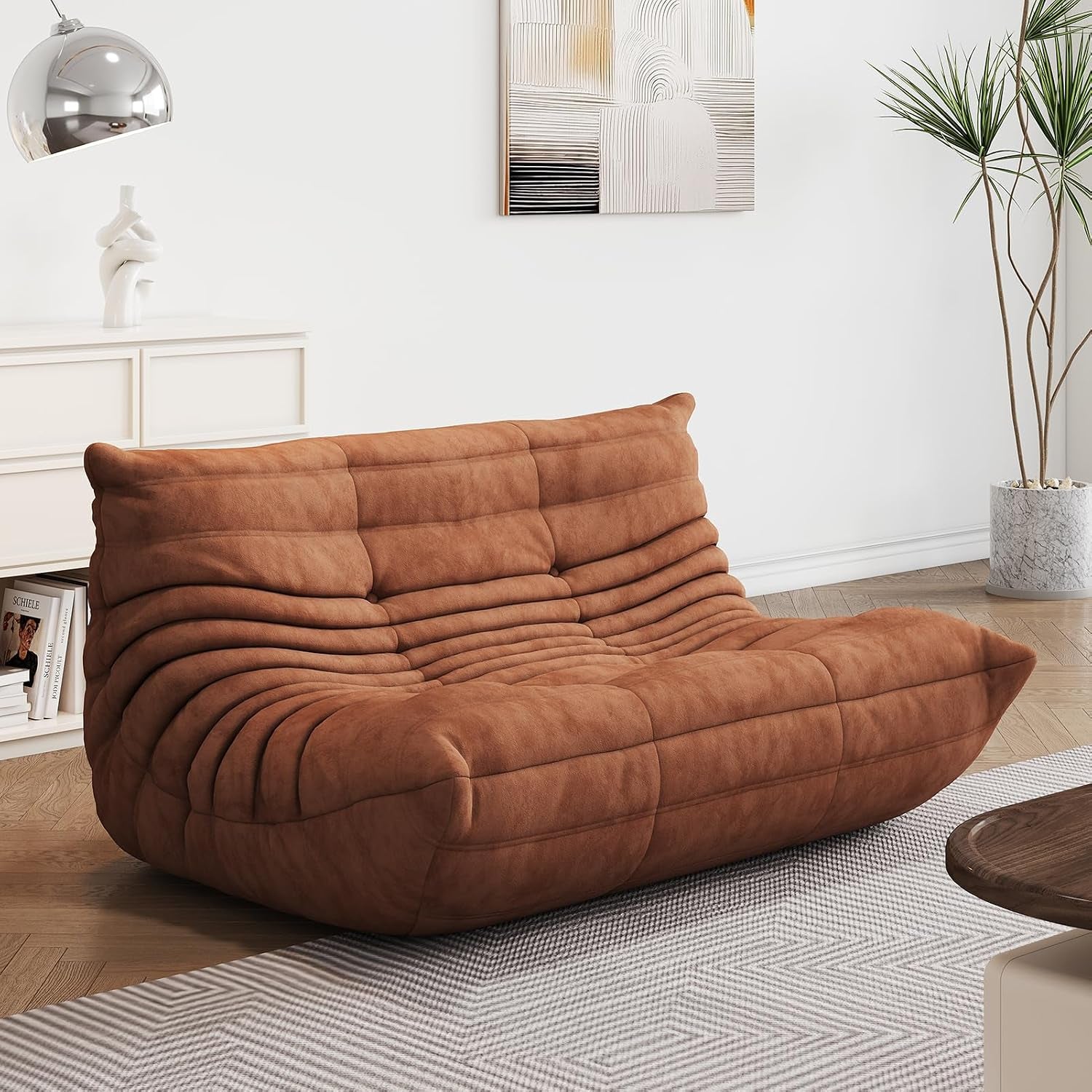 Warm brown two-seat lounge sofa angled toward a wooden coffee table on a patterned rug.