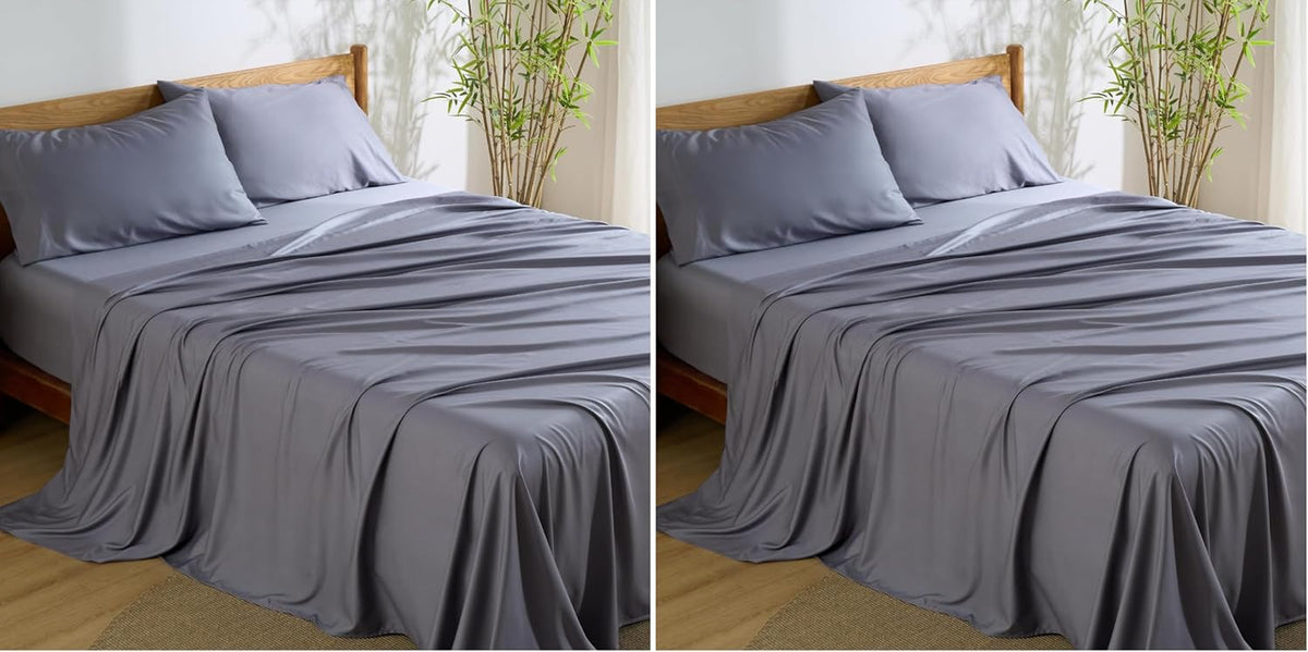 Three-quarter view of a bed dressed in slate-gray silky sheets with two matching pillows and a wooden headboard.