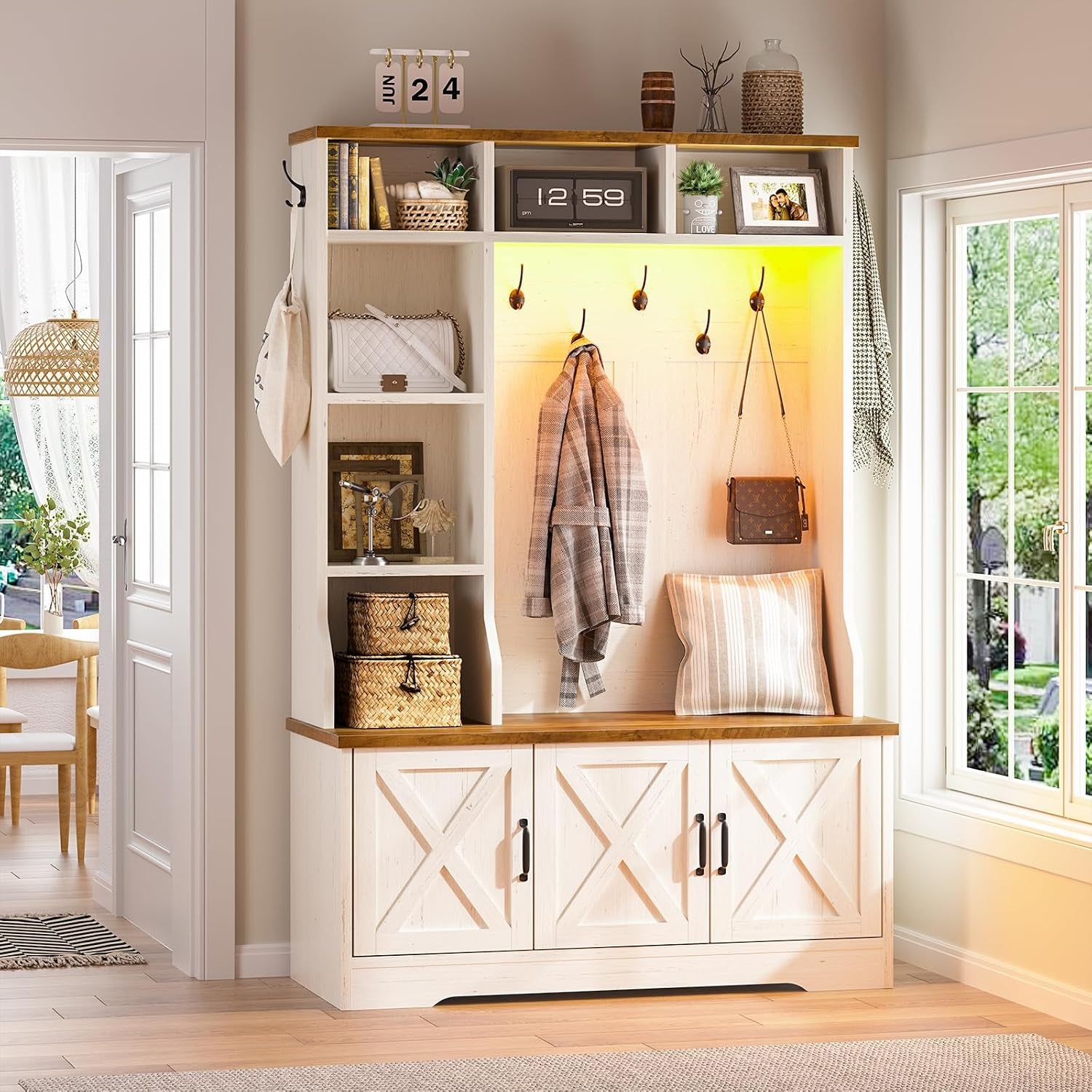 Front view of a white hall tree with a brown wood top, yellow-lit cubby, three lower doors and decorative shelving