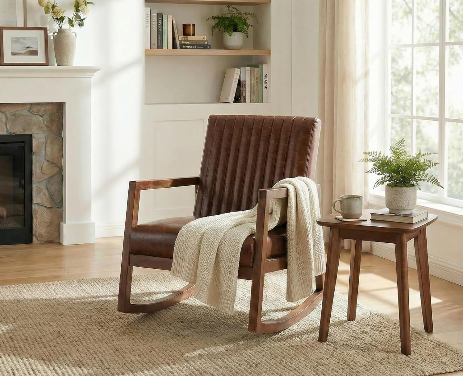 Chair beside a window and fireplace with a chunky knit throw over the arm and a small wooden side table with plant and mug