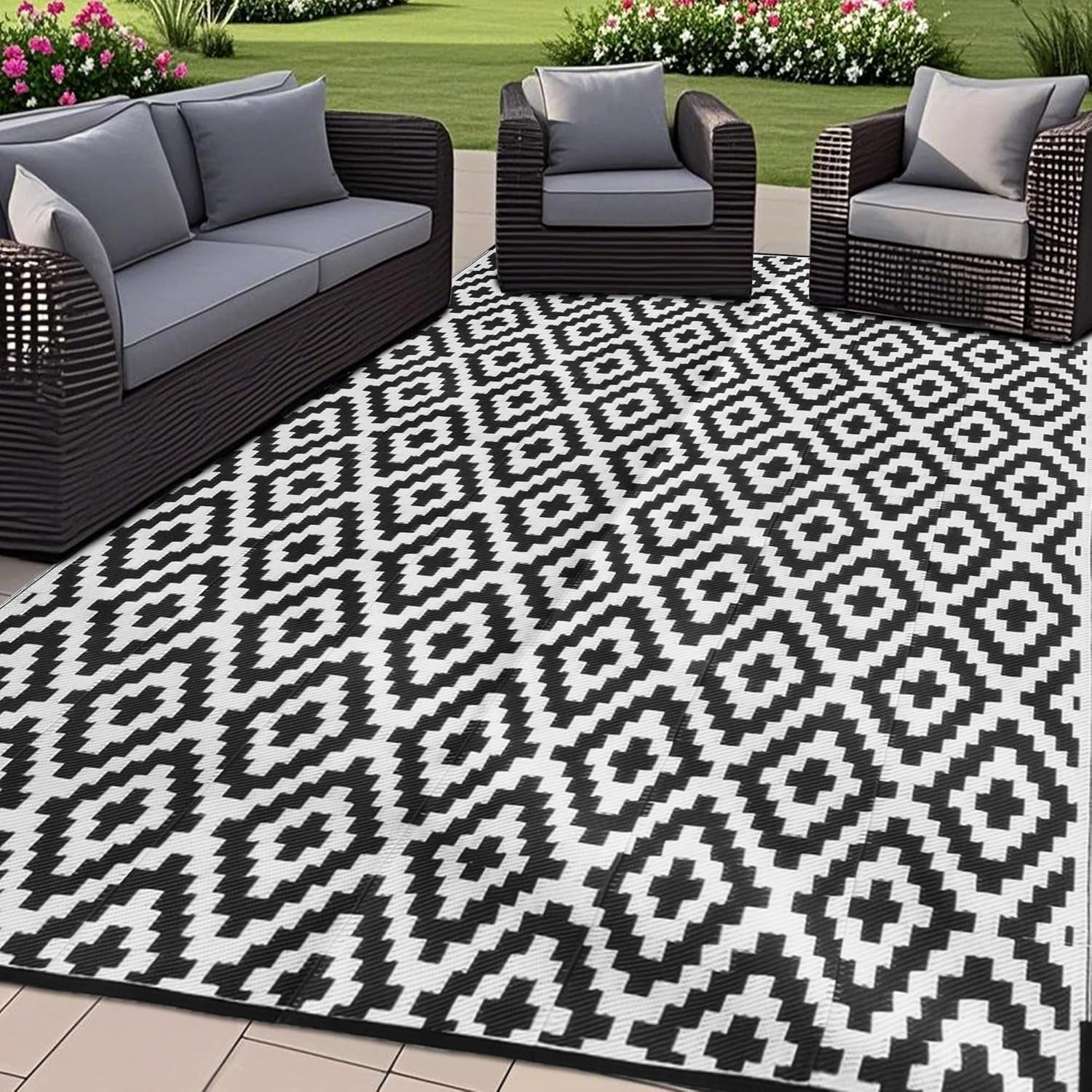 Patio seating on a white-and-black geometric outdoor rug next to grass and flowers