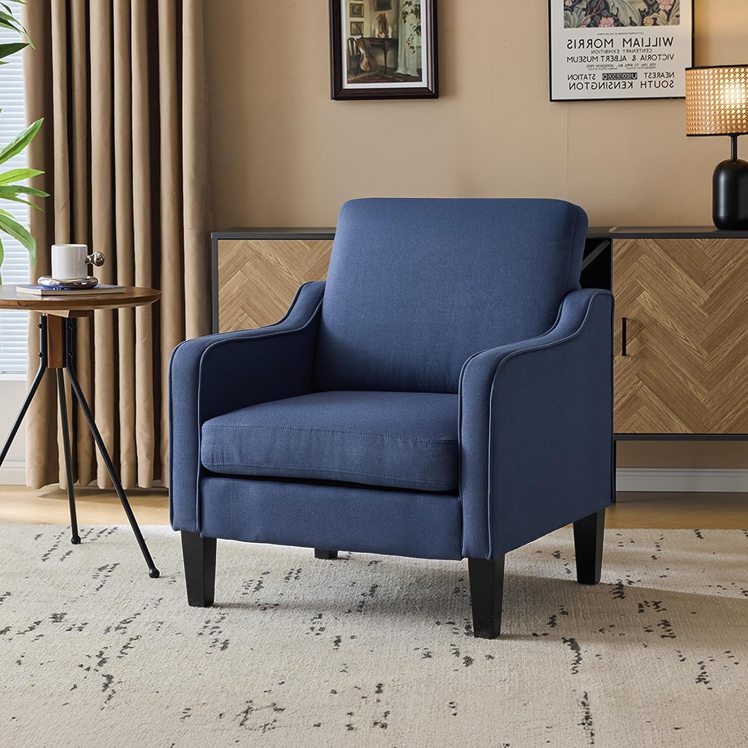 Navy blue upholstered accent chair placed on a rug beside a small side table in a living room.