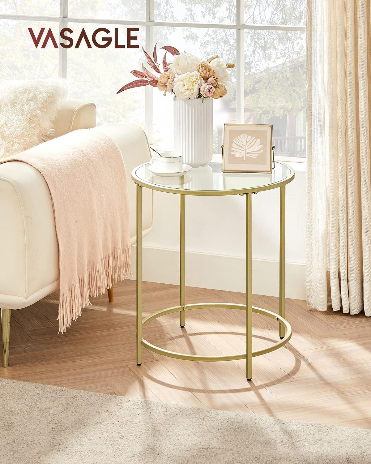 Gold side table next to a sofa by a window showing full table in a living room setting