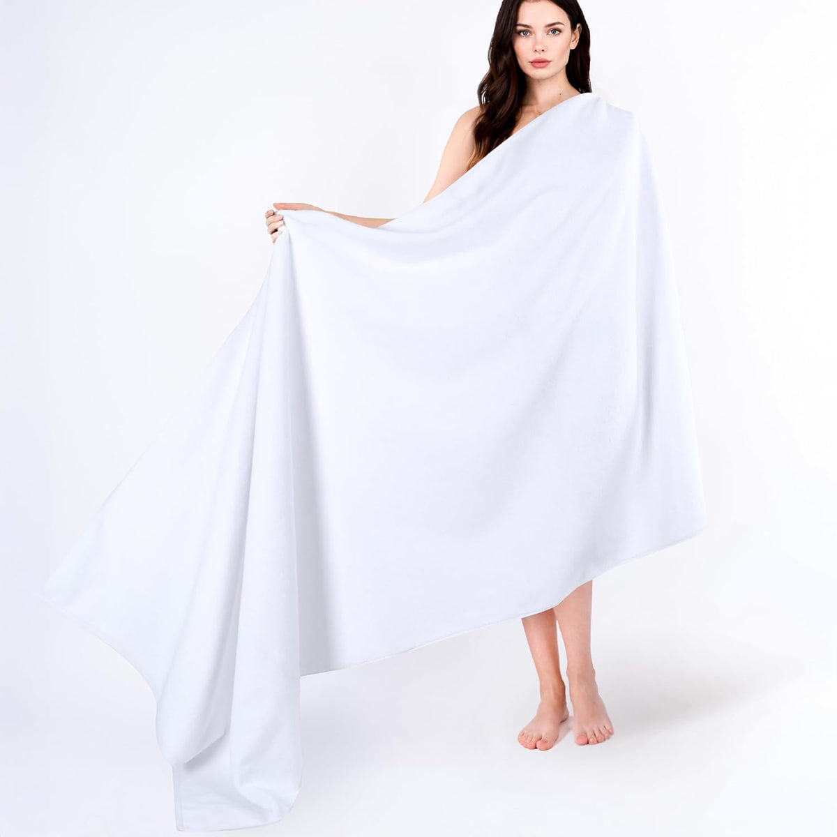 Model wrapped in and holding a large white towel displayed full length