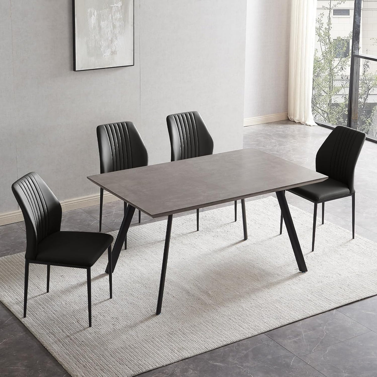 Angled overhead view of the table and four black PU chairs showing stitched chair backs and tapered metal legs.