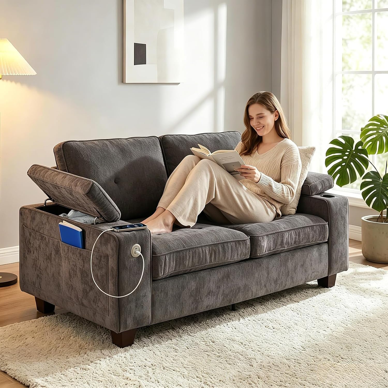 Side view of a dark gray loveseat showing an open armrest storage compartment and a USB cable plugged into the side port.