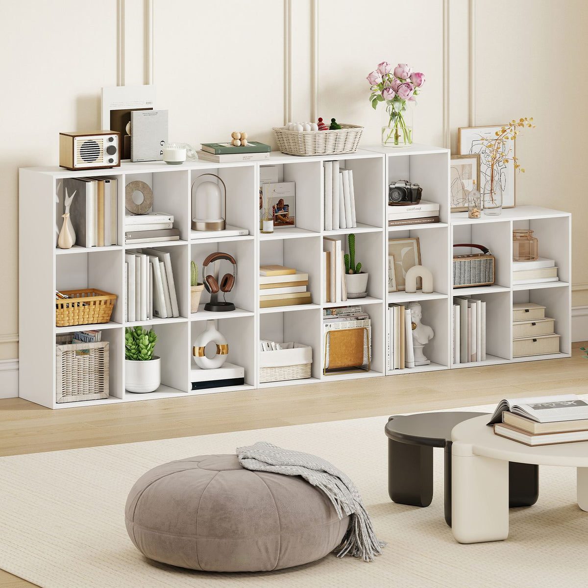 A long arrangement of white cube shelves displays books, baskets, plants, and decorative objects.