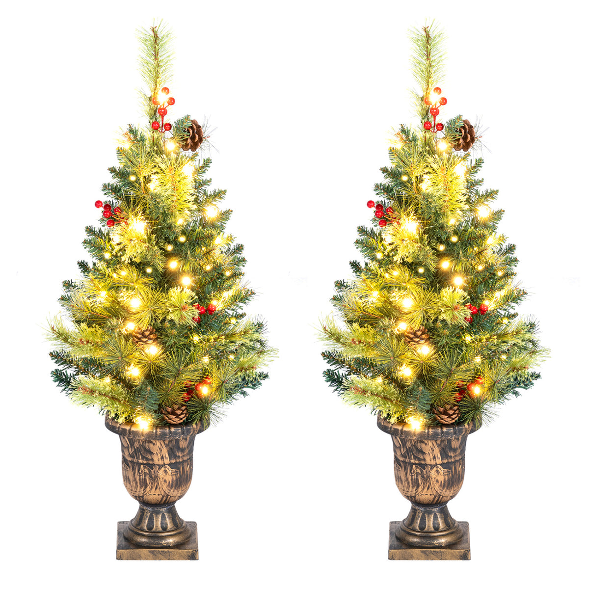 Two glowing evergreen tabletop trees in matching urn-style planters, decorated with berries and pinecones.