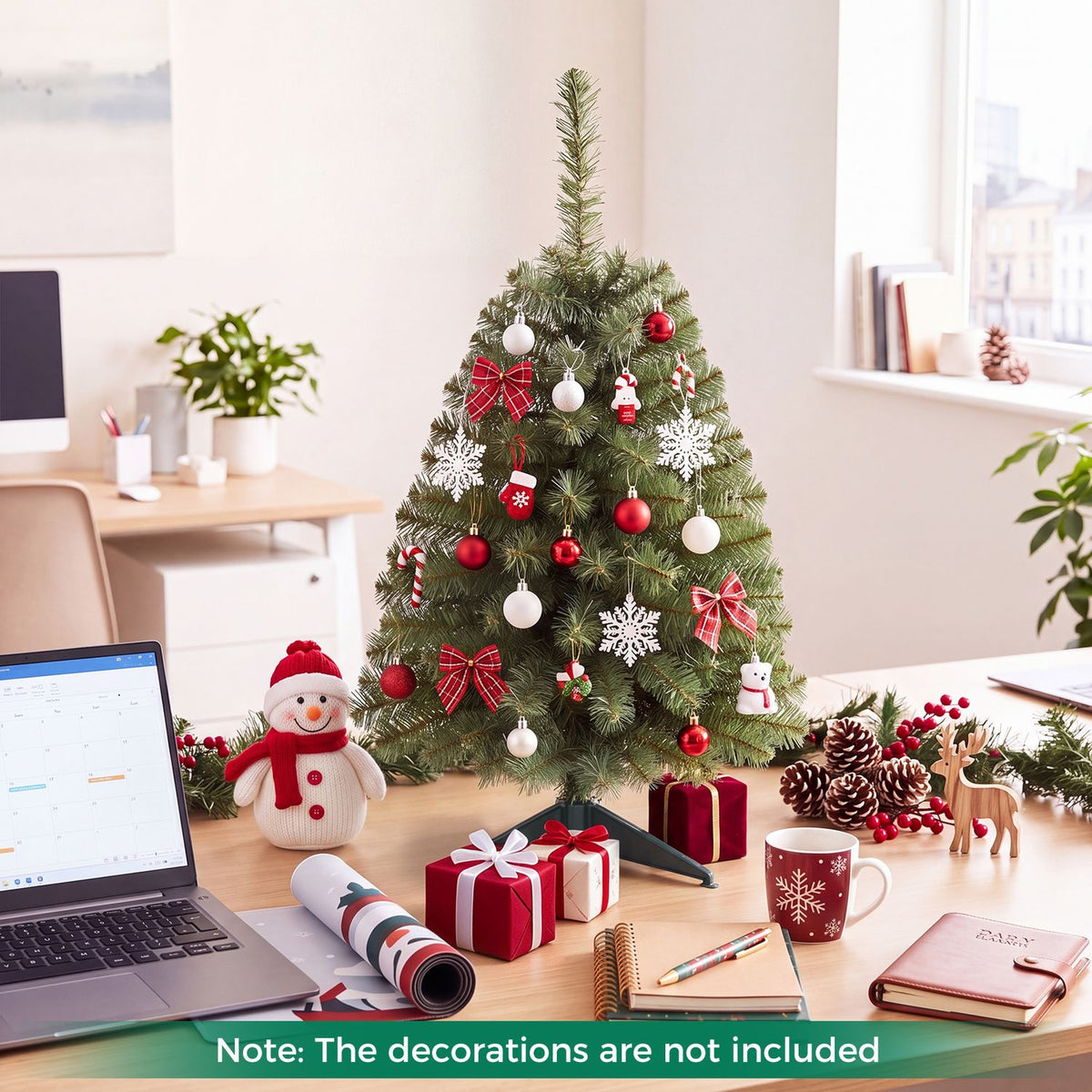 A decorated Christmas tree sits on a desk among gifts, a laptop, notebooks, and holiday ornaments.