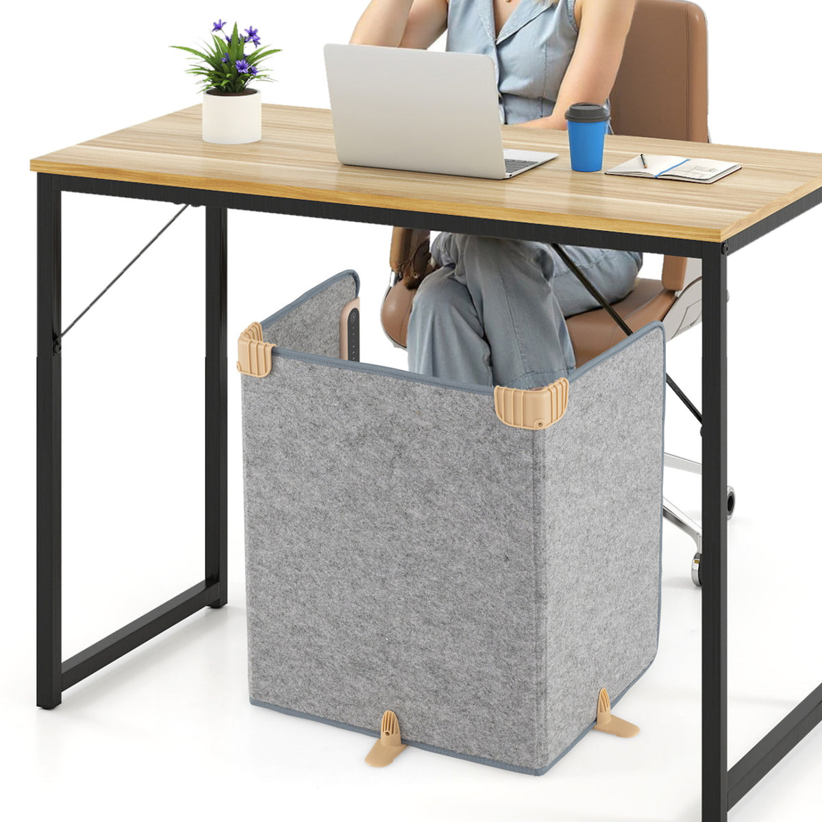 A person sits at a desk with a gray folding heater enclosure positioned around their legs beneath it.